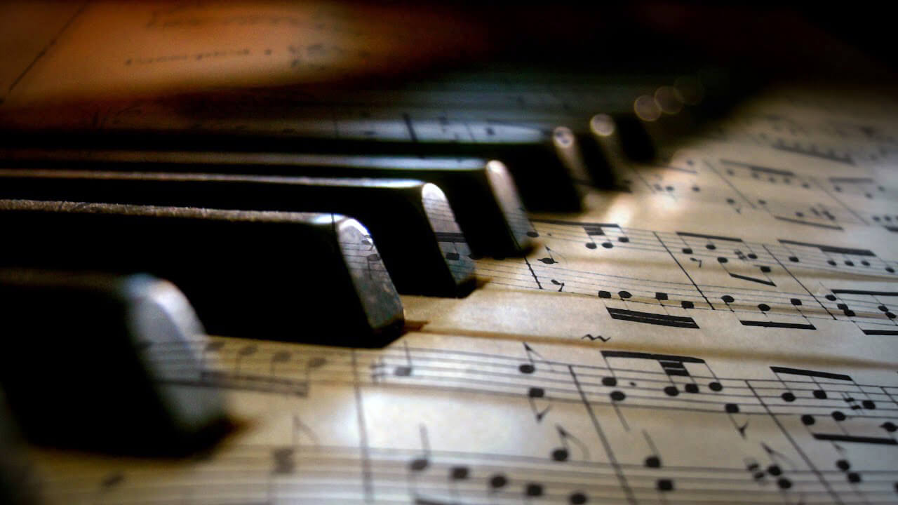 piano keys with sheet music on surface of white keys